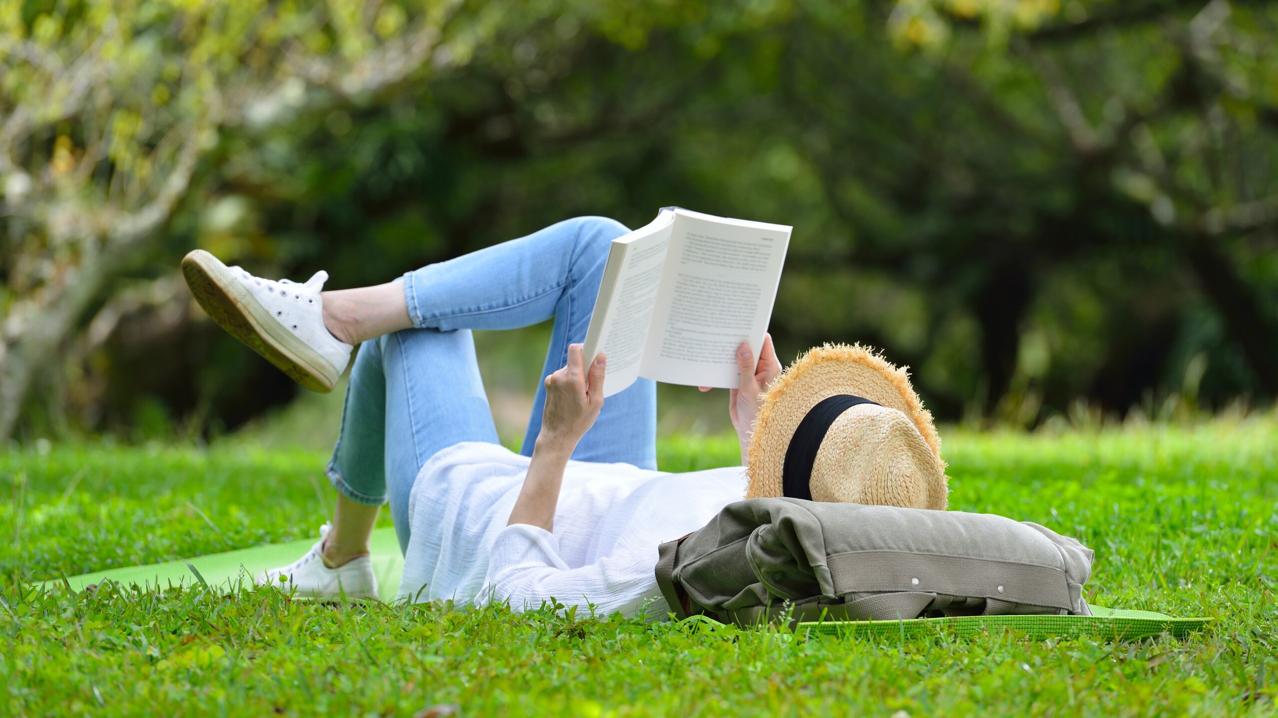 Happy,Woman,Lying,On,Green,Grass,Reading,A,Book,In Photo by amenic181 / Shutterstock.com